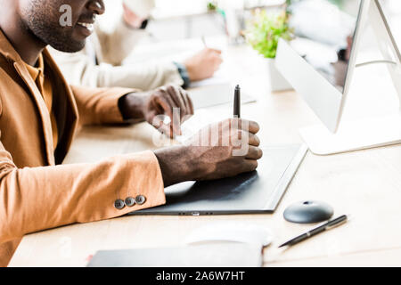 cropped view of african american businessman using tablet while sitting near colleague in office Stock Photo