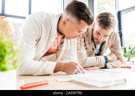 selective focus of two young businessmen analyzing documents while working on startup project together in office Stock Photo