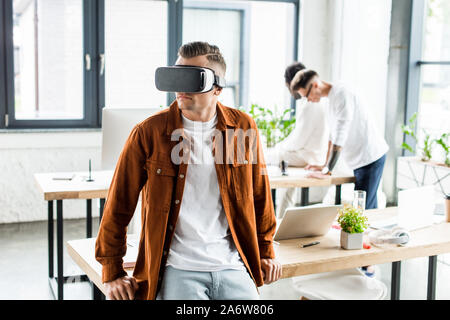 young businessman using vr headset while multicultural colleagues working in office Stock Photo