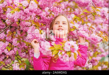 Kid enjoying pink cherry blossom. Tender bloom. Pink is the most girlish color. Bright and vibrant. Pink is my favorite. Little girl enjoy spring. Kid on pink flowers of sakura tree background. Stock Photo