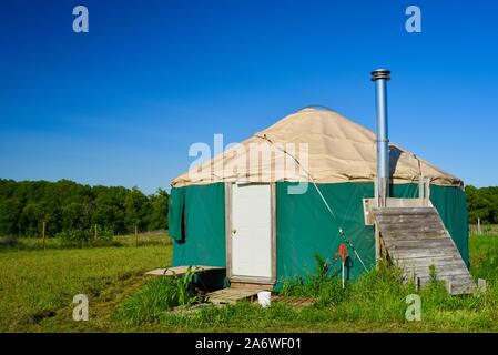 Traditional canvas yurt home with chimney at a small farm outside during sunny daytime in summer, in Decorah, Iowa, USA. Stock Photo