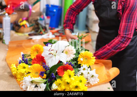 Florist at work. Woman hands making beautiful bouquet of flowers . Stock Photo