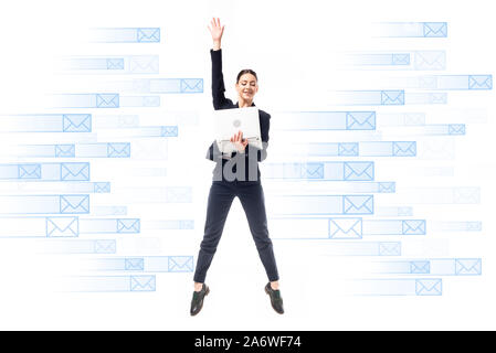 smiling businesswoman using laptop while jumping on background with e-mail icons isolated on white Stock Photo