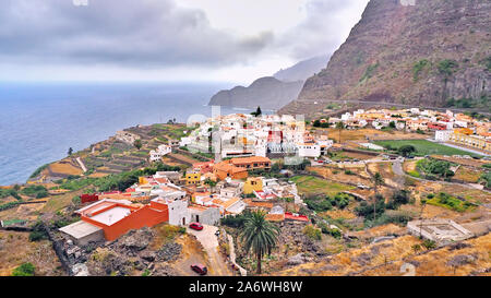 The Canarian island of La Gomera with a view from far above the small colorful town by the sea Agulo.Der Atlantic is blue-gray, the sky overcast in sh Stock Photo