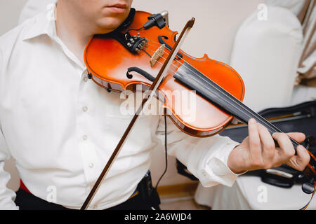 Violin playing viola musician playing . Man violinist classical musical instrument  fiddle .   Close up young fiddler dressed elegantly playing on woo Stock Photo