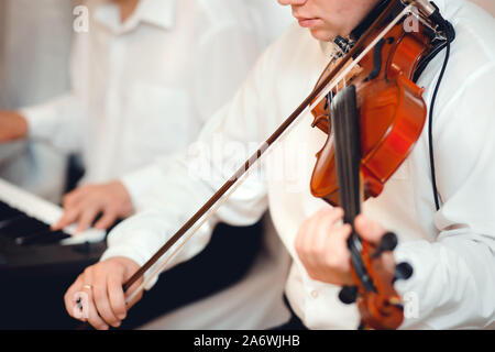 Violin playing viola musician. Man violinist classical musical instrument  fiddle playing on wedding.   Close up young fiddler dressed elegantly playi Stock Photo