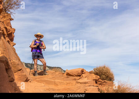 Woman hiking alone on the South Kaibab Trail in the Grand Canyon under a blue sky on a narrow and dangerous trail Stock Photo