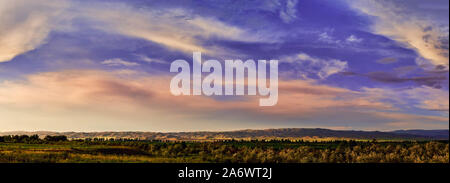 Panorama. Fairytale dawn, sunset with bright colorful clouds, on a background of rolling hills Stock Photo