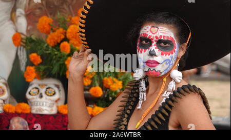 Young woman wearing sugar skull makeup and huge sombrero at Dia de los Muertos event at Mission San Luis Rey. Stock Photo