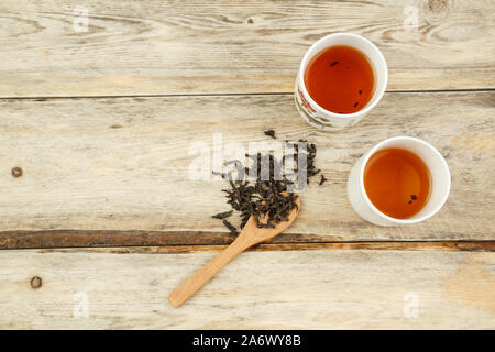 black Indian natural tea on a spoon and brewed in a glass on a wooden background. the view from the top Stock Photo