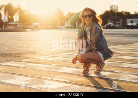 Lovely teenager girl posing at the crosswalk in the sunset. Happy summer, vacation, travel. Summertime. Lifestyle. People, street style and holidays c Stock Photo