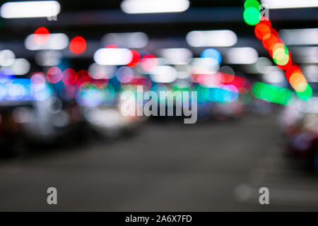 Blurred cars in car parking lot in shopping mall. Bokeh lights background. Abstract blur car parking lot for background. Blurred cars parking and boke Stock Photo
