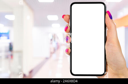 Smartphone mockup in woman hand with business centre background. Modern frameless smartphone mock up with blank white screen. Empty space for text. Co Stock Photo
