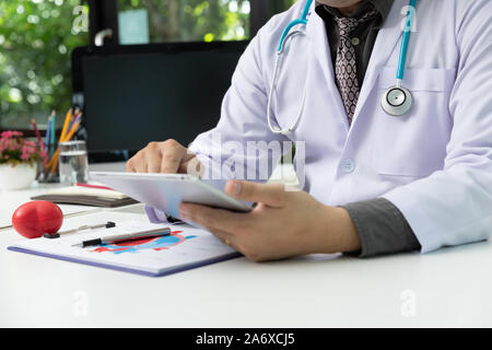 Male doctor using computer tablet in medical office at hospital Stock Photo