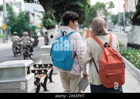 two teenage student smiling walk away while looking back Stock Photo
