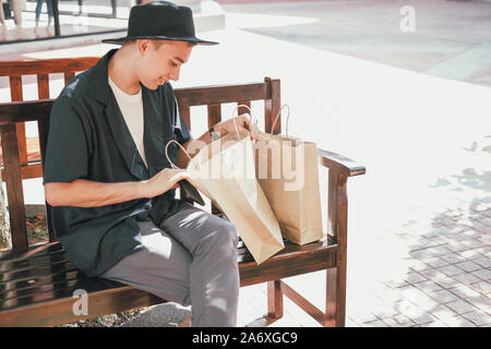 man looking inside shopping bag. consumerism lifestyle Stock Photo