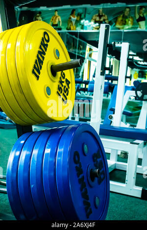 Professional yellow and blue dumbbells and weight plates on the background of the fitness room. Sport equipment. Stock Photo