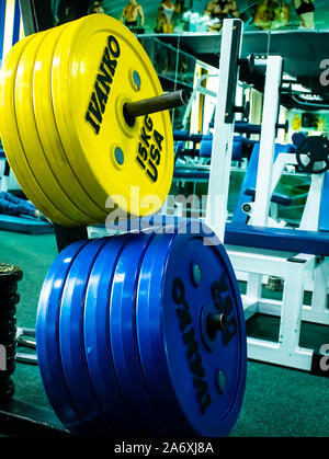 Professional yellow and blue dumbbells and weight plates on the background of the fitness room. Sport equipment. Stock Photo