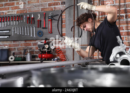man work in home workshop garage with bench grip vise fix a metal on the workbench full of wrenches, diy and craft concept Stock Photo