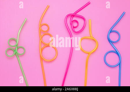 Concept of fun mood. Colorful cocktail straws on pink paper background. Plastic curved straws, tubes. Abstract frame, card with minimal design. Modern Stock Photo