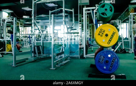 Professional red, green, blue dumbbells and weight plates on the background of the fitness room. Stock Photo