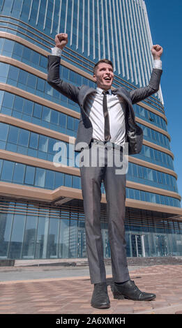 in full growth. a jubilant businessman standing in front of a tall office building. Stock Photo