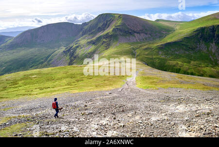A hiker walking down towards the path leading to Crag Hill and Grasmoor from Hopegill Head in the Lake District, England, UK. Stock Photo