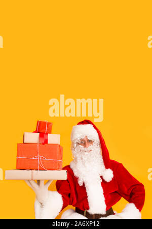 Santa Claus with gift boxes on orange background Stock Photo