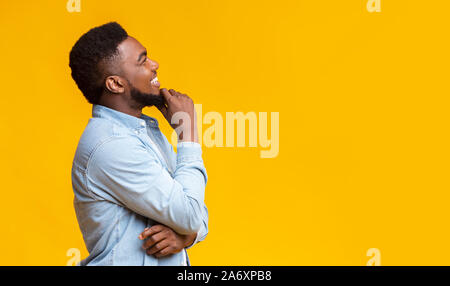 Profile portrait of smiling black guy touching his beard Stock Photo