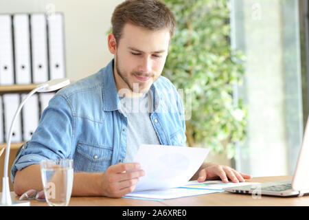 Satisfied entrepreneur working reading paper document sitting on a chair at office Stock Photo