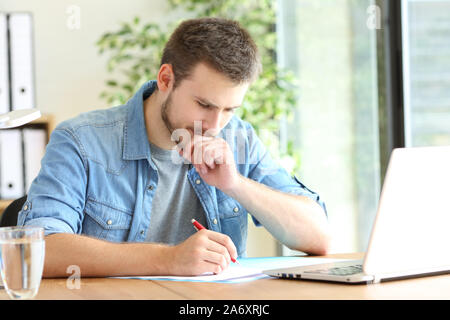Pensive entrepreneur handwriting using pen sitting on a chair at office Stock Photo