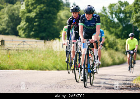 ROTHBURY, NEWCASTLE UPON TYNE, ENGLAND, UK - JULY 06, 2019: Young cyclists on a country lane at the cyclone race event from Newcastle to Northumberlan Stock Photo