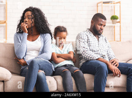 Upset little girl suffer from family conflict, sitting between parents. Stock Photo