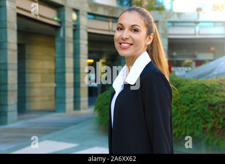 Smiling young business woman posing near office building looking at camera. Stock Photo