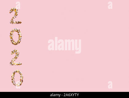 2020 text of gold confetti on pink background Stock Photo