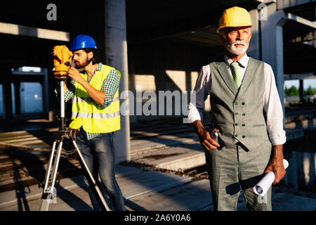 Two satisfied engineers talking at building site with construction structure in background Stock Photo