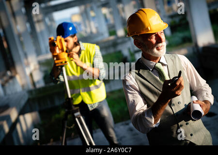 Two satisfied engineers talking at building site with construction structure in background Stock Photo