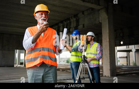 Two satisfied engineers talking at building site with construction structure in background Stock Photo