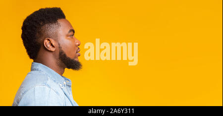 Profile portrait of serious bearded black guy on yellow background Stock Photo