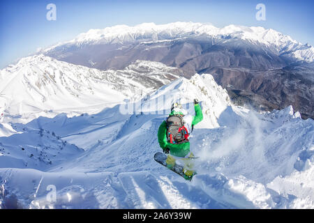 Freerider snowboarder jumping from a slope down in the mountains of the Caucasus, Krasnaya Polyana, Sochi. Stock Photo