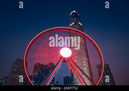 Nightlife in Hong Kong. Observation Wheel against urban skyline with skyscrapers. Stock Photo