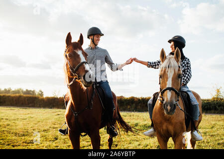 Happy loving couple spending time with horses on ranch Stock Photo