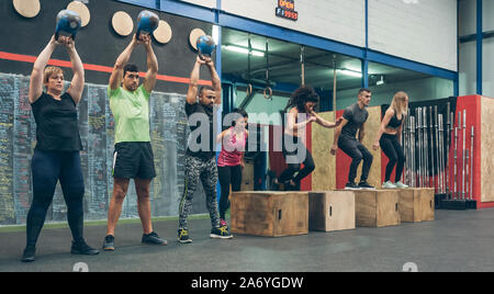 Athletes exercising with kettlebells and doing box jumps Stock Photo