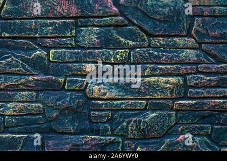 Dark colorful brick wall. Stone wall of different colors. Abstract pattern, grunge background. Mosaic of bricks in modern style. Painted rock texture. Stock Photo