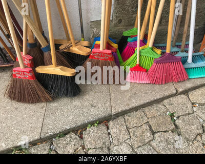 Multi colourful brooms for sale outside a hardware hop nobody in the image Stock Photo