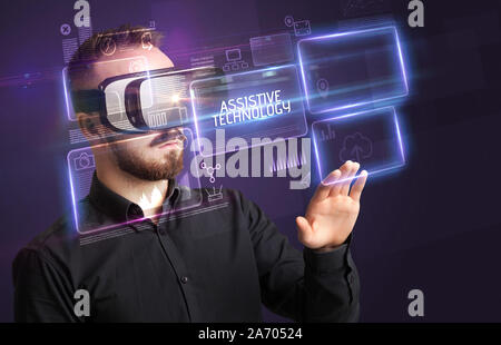 Businessman looking through Virtual Reality glasses with ASSISTIVE TECHNOLOGY inscription, new technology concept Stock Photo