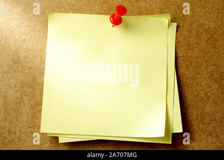 yellow sheet of paper for notes and pushpin Stock Photo