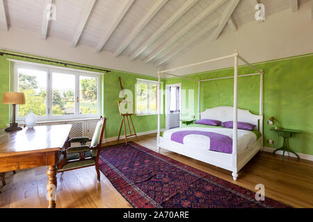 Bedroom with four-poster bed and green wall. No one inside Stock Photo