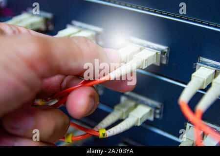 Technician connect fiber cable network to switch port in server room , Concept internet network management Stock Photo