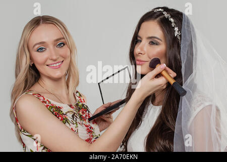 Woman makeup artist holding make up brush and applying cosmetic on fashionable bride Stock Photo
